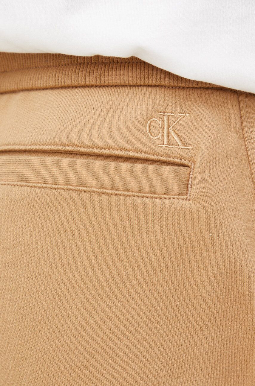 Calvin Klein Jeans Bavlněné tepláky hnědá barva s potiskem - Pepit.cz